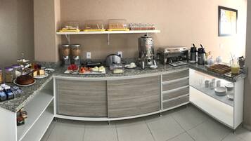 A modern kitchen with a curved island, equipped with a coffee maker, blender, and various food items.
