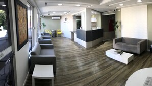 A modern reception area with a reception desk, seating area, and a television mounted on the wall. - Cerrado Hotel (Campo Grande)