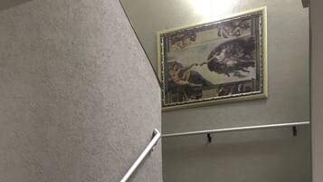 A staircase with a handrail, a wall-mounted picture, and a ceiling-mounted exit sign.