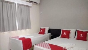 A hotel room with two beds, each with a red pillow and a white blanket. - Cerrado Hotel (Campo Grande)