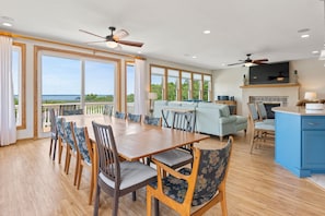 A spacious dining area with a large wooden table and chairs, a light blue sofa, and a kitchen area with blue cabinets.