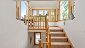Una escalera con barandillas de madera y peldaños alfombrados que suben a un piso superior.