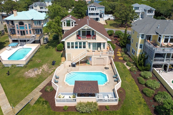 Ein großes, zweistöckiges Haus mit Swimmingpool, einer überdachten Terrasse und mehreren Balkonen.