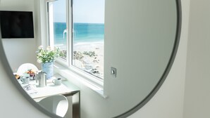 Una stanza con vista sulla spiaggia, una scrivania con un vaso di fiori e una sedia.