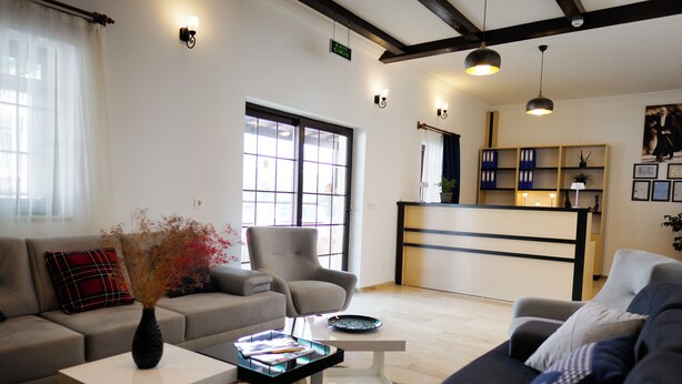 A modern living room with a sofa, armchair, and coffee table. There is a kitchen area with a counter and shelves in the background. - Villa Hania (Manavgat)
