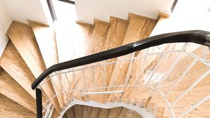 A spiral staircase with wooden steps and a black handrail, leading to an upper floor. - Villa Hania (Manavgat)