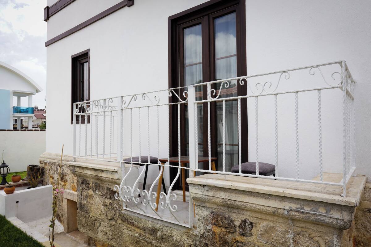 A white building with a stone base and a white metal balcony railing.