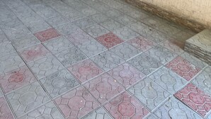 Une façade d’immeuble avec de grandes fenêtres, un trottoir dallé et une porte.