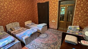 Une chambre avec deux lits, une armoire, une porte et un ventilateur.