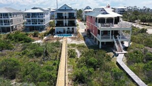 A beachfront property with multiple buildings, including a two-story house with a balcony and a swimming pool.