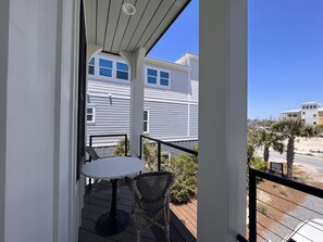 Ein Balkon mit Tisch und Stühlen, mit Blick auf eine Wohngegend mit Häusern und Palmen.