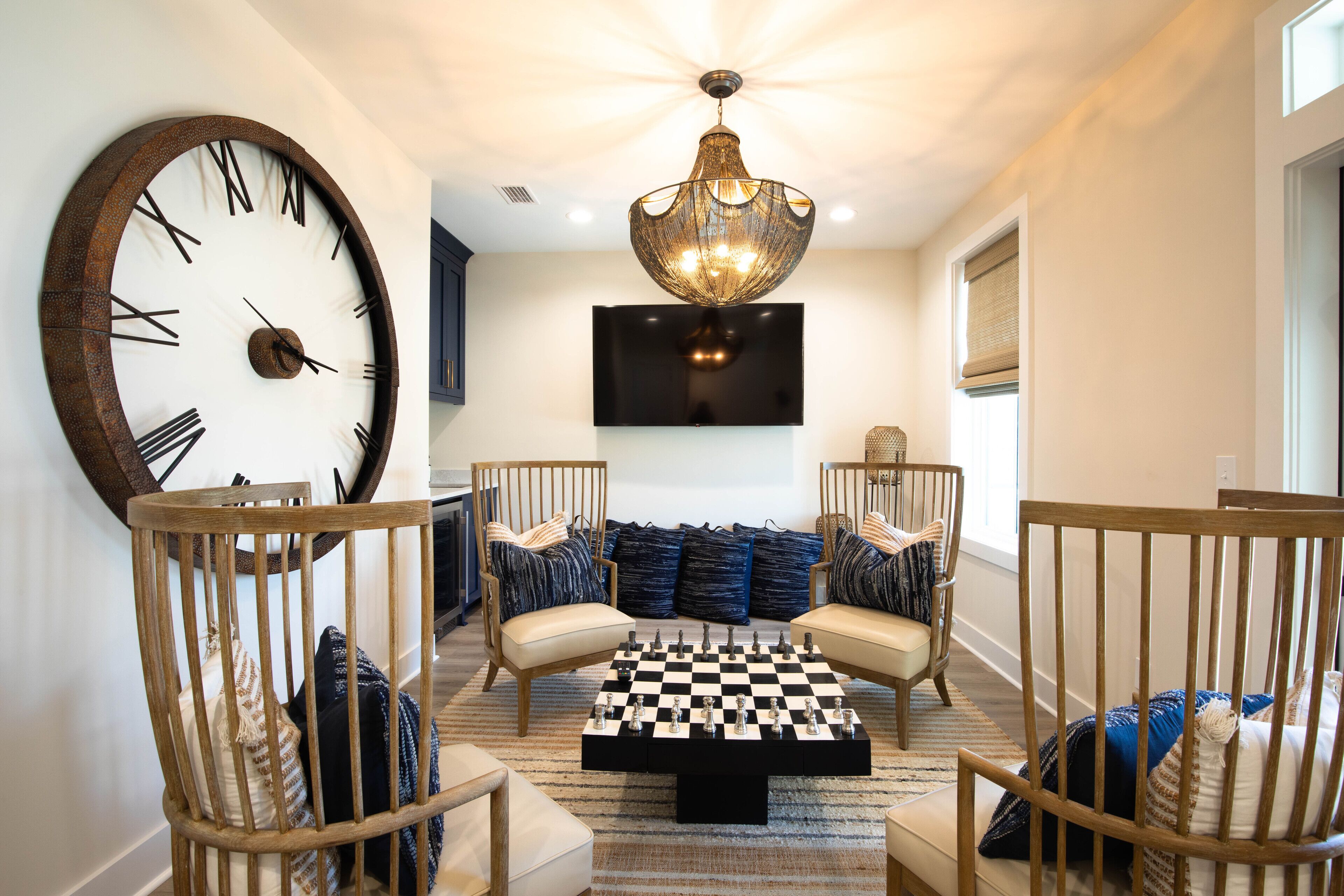 A spacious living area with a large wall clock, a chess table, and modern seating.