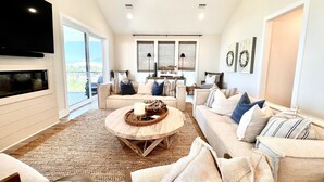 A spacious living room with a large TV, comfortable seating, and a view of the outdoors.