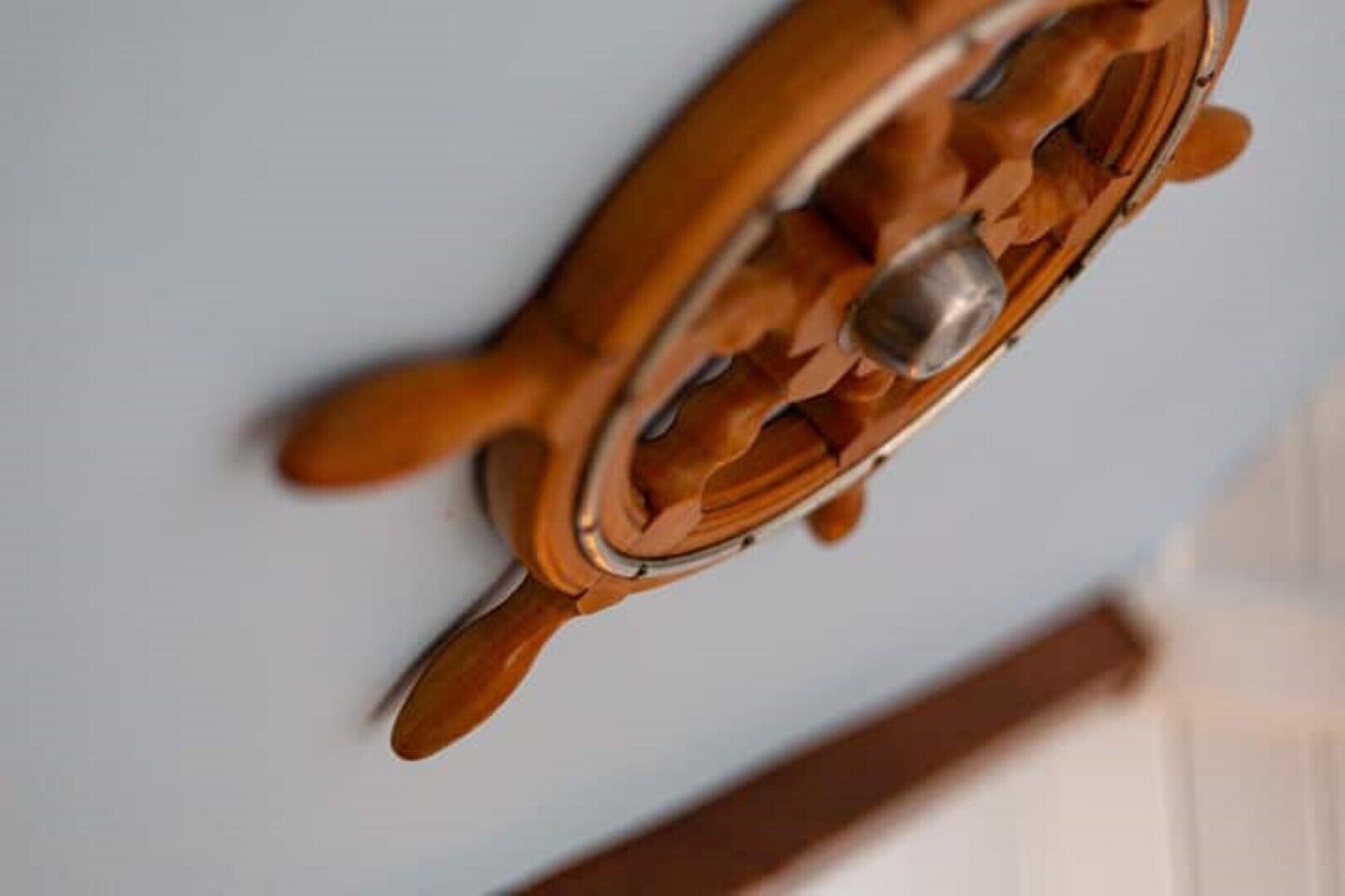 A wooden ship's wheel mounted on a wall.