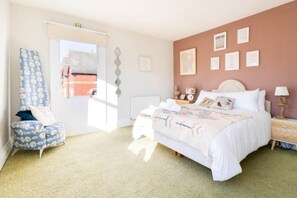 Quarto com cama, cadeira, radiador e janela.