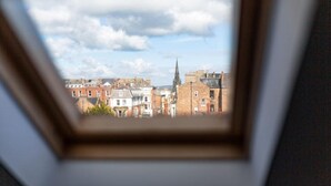 Uitzicht door een raam op een stadsgezicht met gebouwen en een kerktoren.