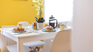 Een ontbijttafel met gebak, een koffiepot en een bloempot.