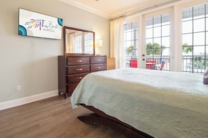 Une chambre à coucher comprenant un lit, une commode, un miroir et une fenêtre donnant sur l’extérieur.