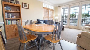 Un coin repas avec une table ronde et des chaises, une bibliothèque et une vue dégagée grâce à de grandes fenêtres.