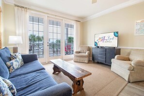 Una sala de estar con un sofá, un banco de madera, un televisor, una silla y un armario.
