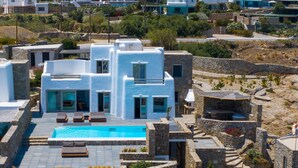 A modern building with a swimming pool, stone architecture, and a blue logo on the ground. - Luxury Villa Agavi Ideal for Events (Mykonos)