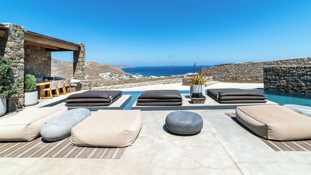 A poolside area with lounge chairs and a view of the sea. - Luxury Villa Agavi Ideal for Events (Mykonos)