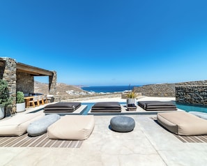 Un espace aménagé au bord de la piscine, avec des chaises longues et une vue sur la mer.