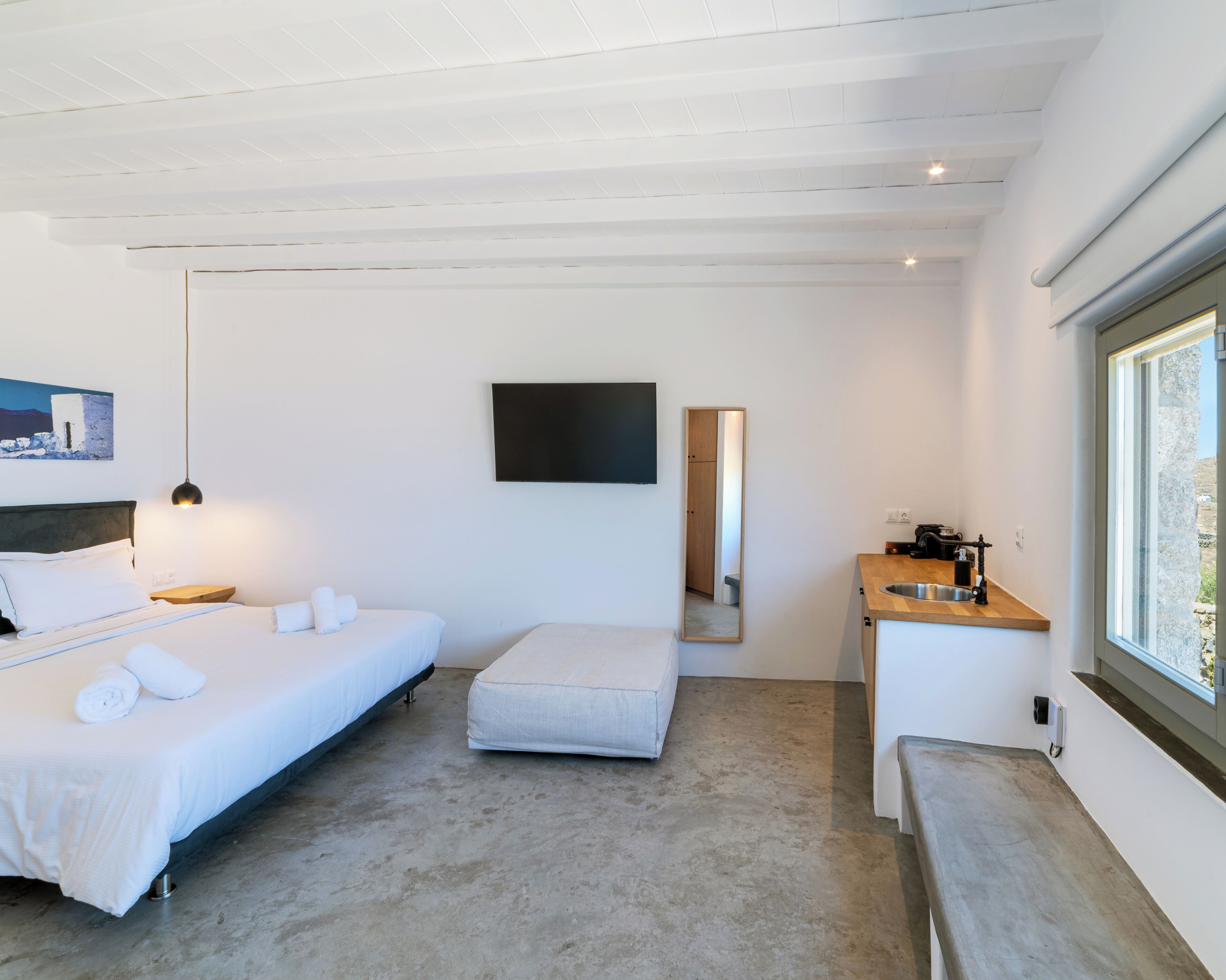 A modern bedroom with a bed, bedside table, and a small desk with a mirror.