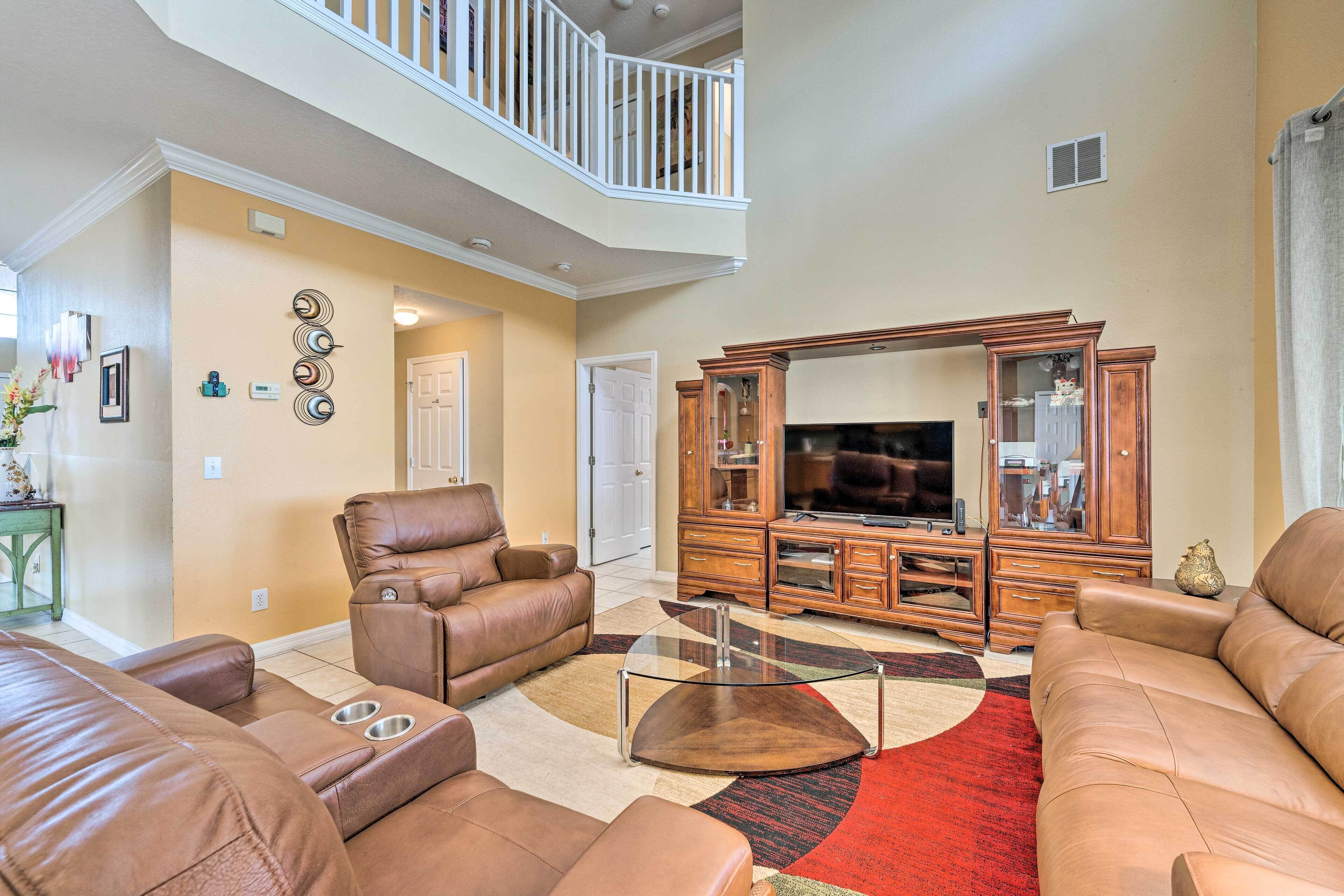 A spacious living room with leather sofas, a glass coffee table, and a wooden entertainment center.