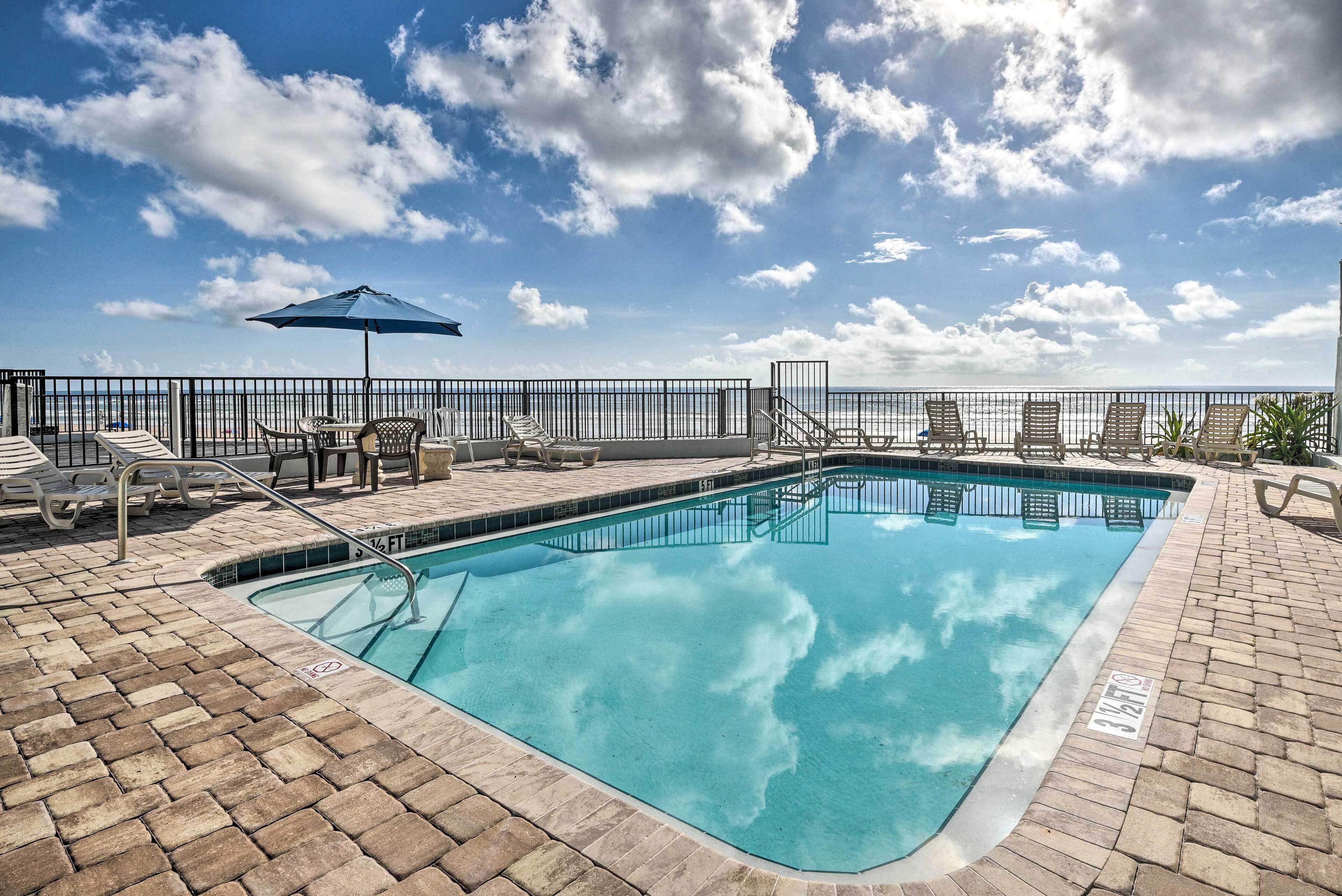 A rectangular pool with a tiled edge, surrounded by a brick patio and metal railings.