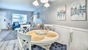 A dining area with a round table, white chairs, and a ceiling light fixture. - Airy Oceanfront Condo: Steps to Daytona Beach (Daytona Beach)