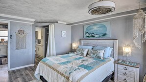 Ein Schlafzimmer mit einem Bett, Nachttischen, einer Chandelierleuchtre und Wandbild sowie einem Wandbehang aus Makramee.