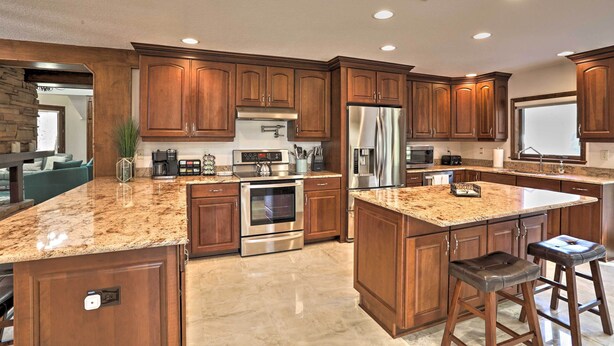 A modern kitchen with granite countertops, stainless steel appliances, and wooden cabinetry. - The Peacock Farm Largo Home + Outdoor Oasis! (Seminole)