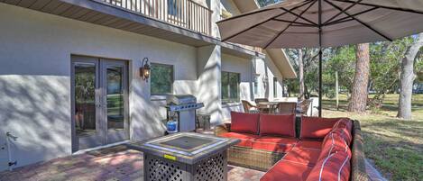 A patio with a grill, outdoor seating, and a covered area.