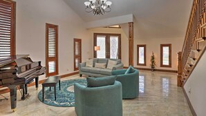 A spacious living room with a grand piano, a large sofa set, and a chandelier. - The Peacock Farm Largo Home + Outdoor Oasis! (Seminole)