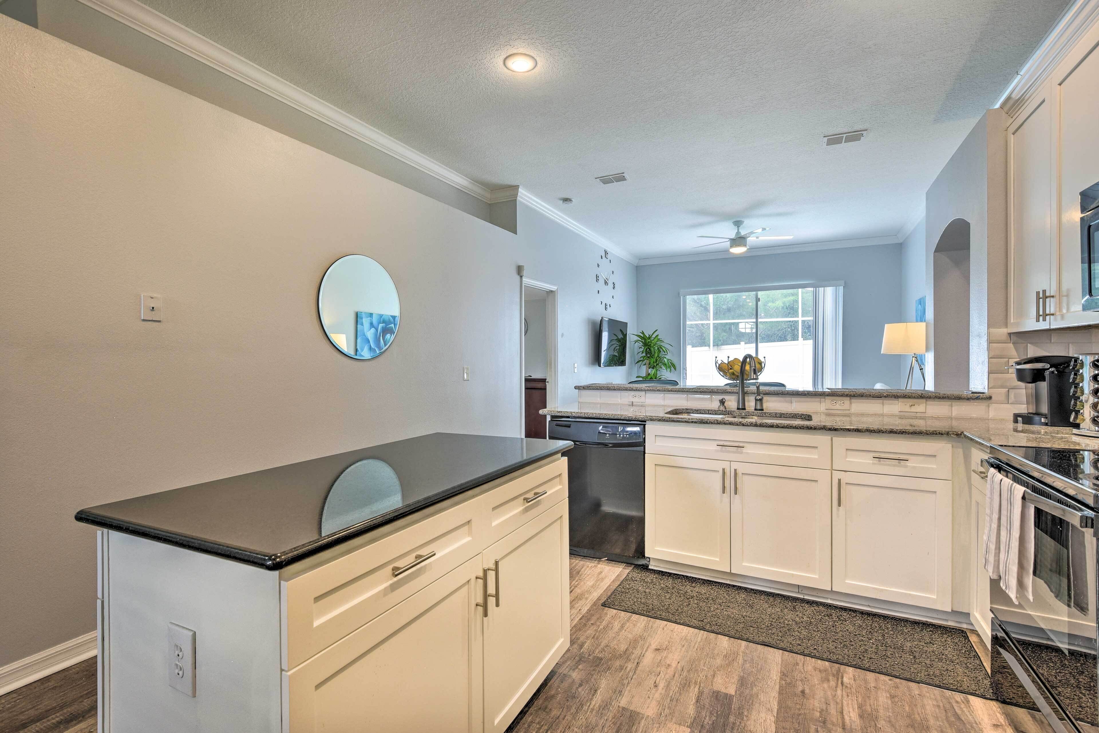 A modern kitchen with white cabinetry, a black countertop, and a dishwasher.
