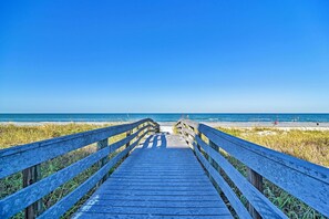 A wooden boardwalk leading to a beach with clear skies.