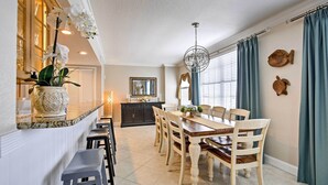 Een eetgedeelte met een houten tafel en stoelen, een kroonluchter en decoratieve objecten aan de wanden.