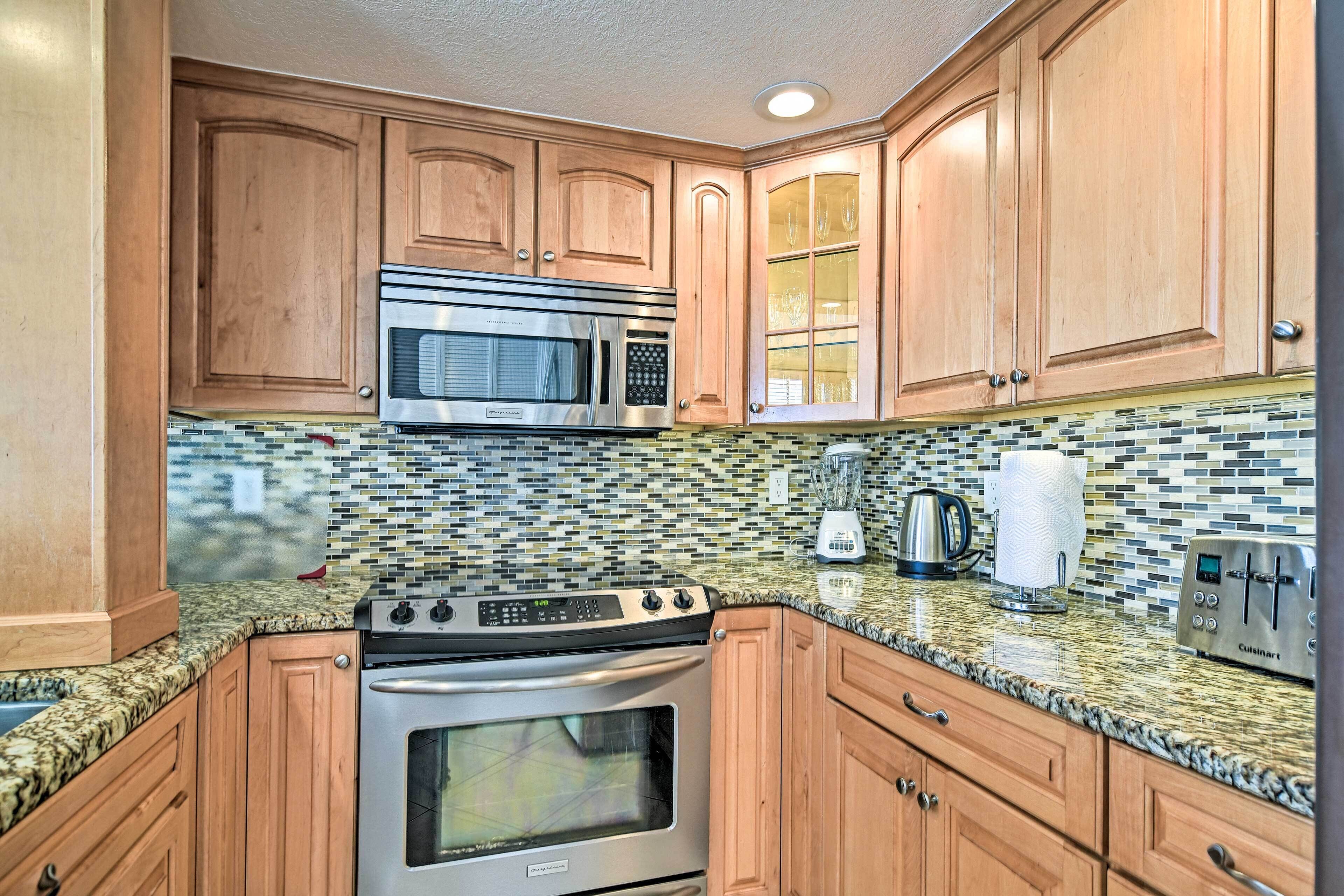 A kitchen with wooden cabinets, a stainless steel stove, a microwave, a toaster, and a tiled backsplash.