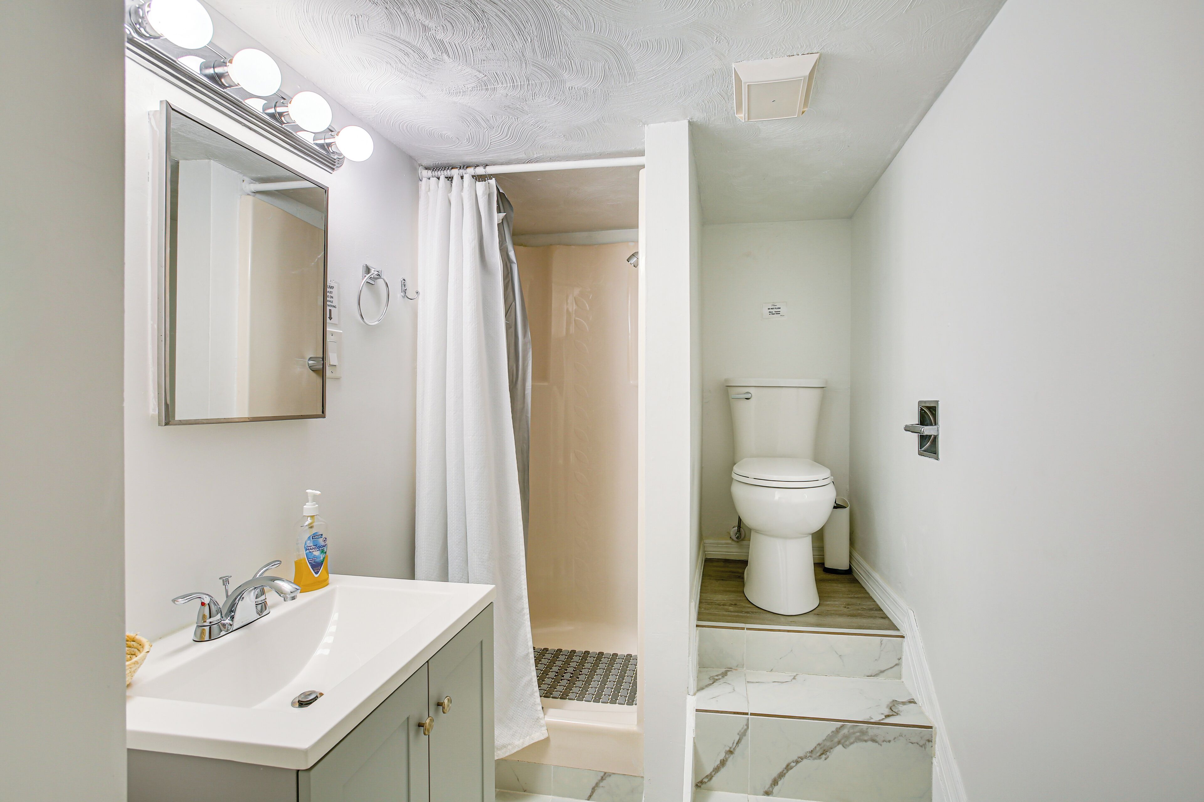 A bathroom with a sink, mirror, and shower.