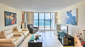 A spacious living room with a sofa set, a coffee table, a flat-screen TV, and artwork on the walls. - Bayfront Miami Condo w/ Resort Perks & Ocean Views (Miami)