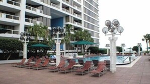 A hotel with a pool area, lounge chairs, and a large building with balconies. - Bayfront Miami Condo w/ Resort Perks & Ocean Views (Miami)