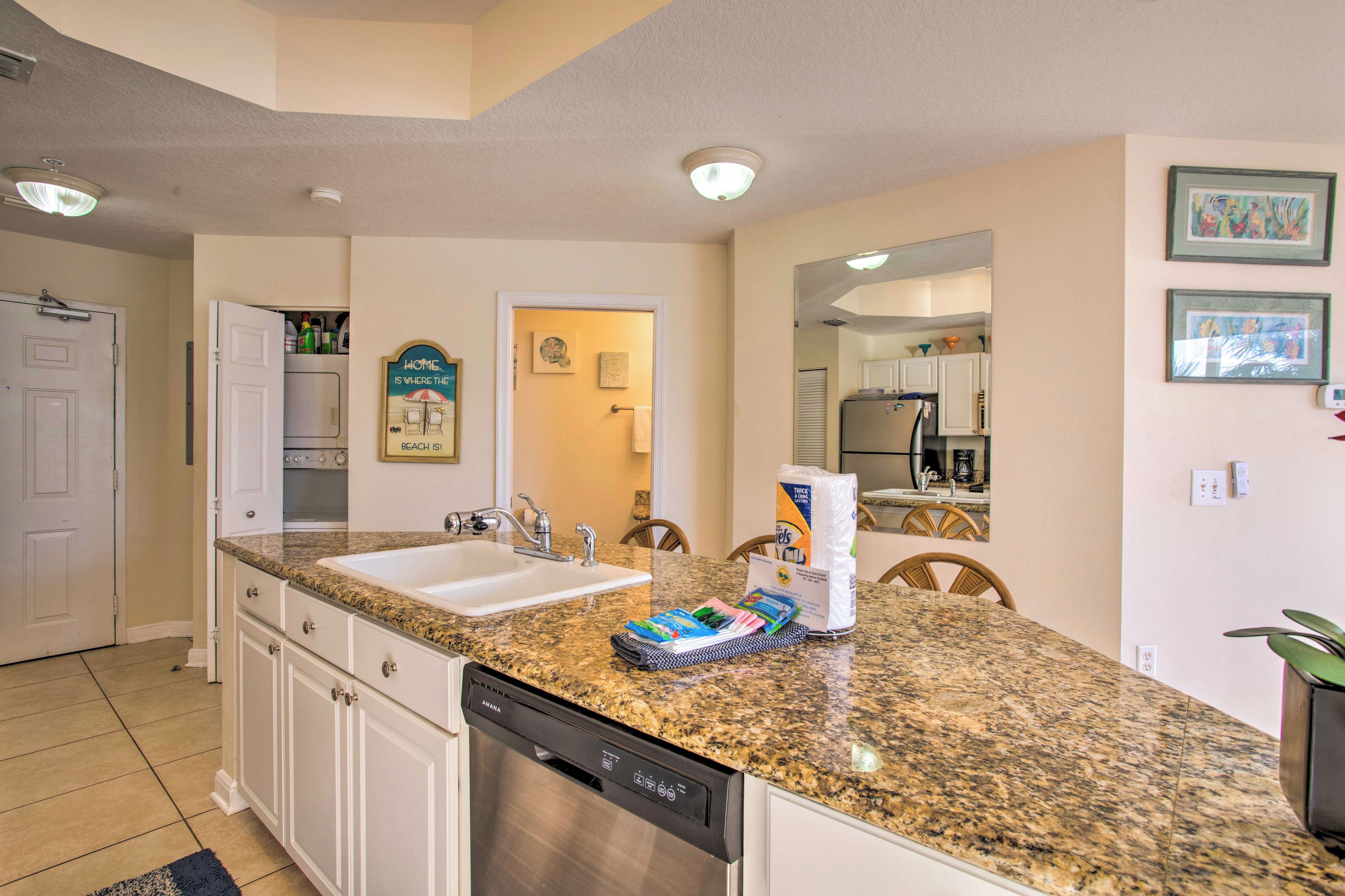 A kitchen with granite countertops, white cabinets, a dishwasher, and a double sink.