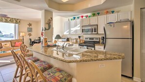 A kitchen with a granite countertop, white cabinets, a refrigerator, and a microwave. - Best Views in St Pete for Dolphin Viewing (St. Petersburg)