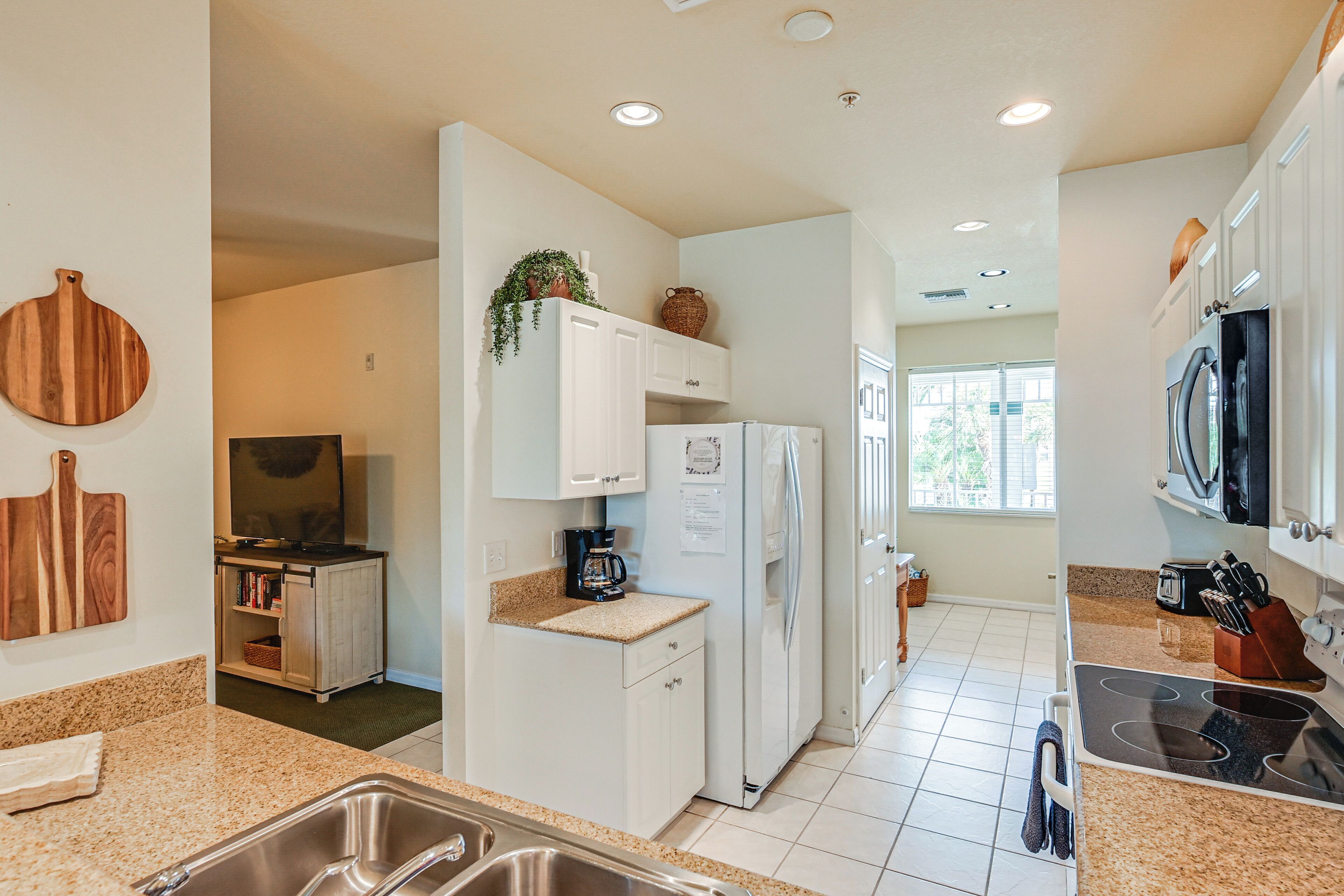 A modern kitchen with white cabinets, a built-in oven, and a stainless steel sink.