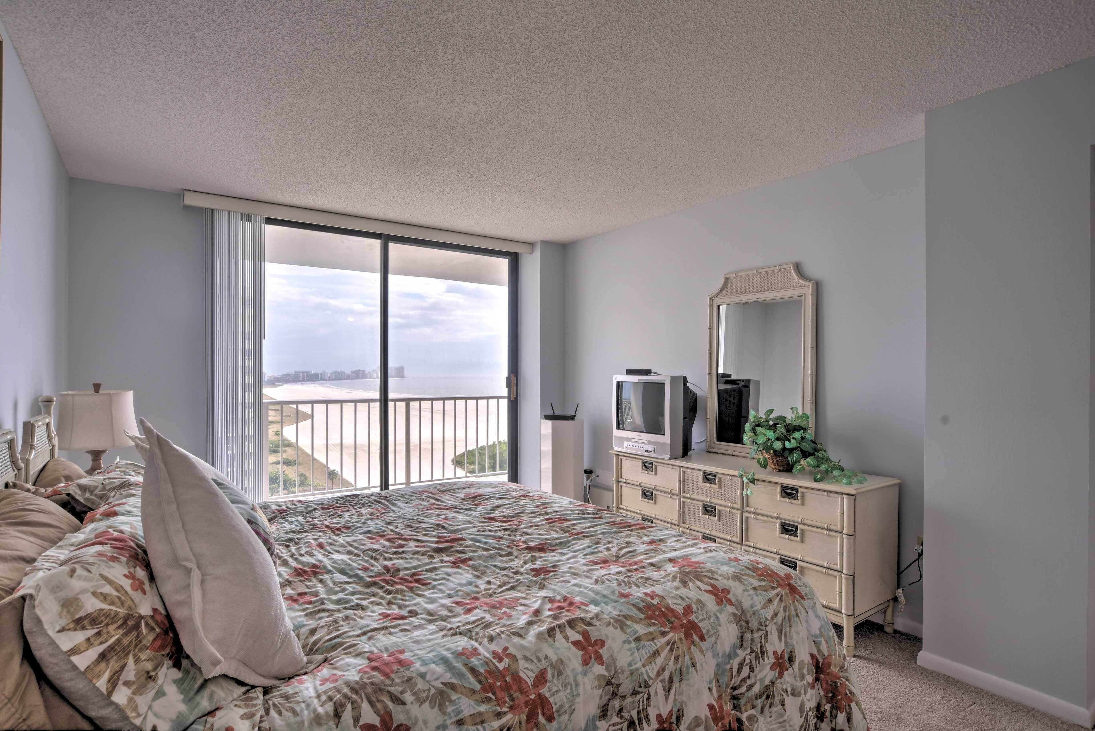 Un dormitorio con una cama grande, un tocador, un televisor y un balcón con vistas.