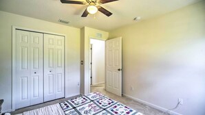 A bedroom with a bed, a ceiling fan, and two white doors. - 'banzai Palm Bay' Home Near Parks & Beaches! (Palm Bay)