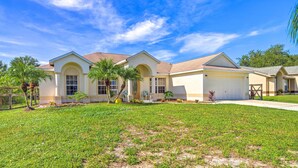 A two-story house with a white exterior, a garage, and a well-maintained lawn. - 'banzai Palm Bay' Home Near Parks & Beaches! (Palm Bay)