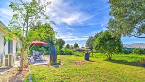 A backyard with a patio, outdoor furniture, a red umbrella, and a garden. - 'banzai Palm Bay' Home Near Parks & Beaches! (Palm Bay)