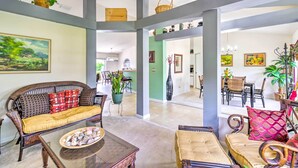A spacious living area with a sofa, coffee table, and chairs. There are plants, a painting, and a dining area visible. - 'banzai Palm Bay' Home Near Parks & Beaches! (Palm Bay)